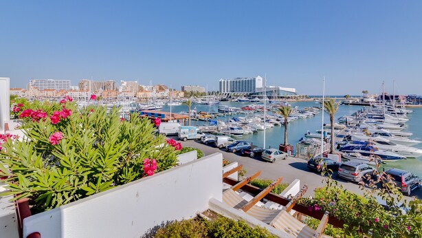 A marina with boats, a clear sky, and buildings in the background. - São Vicente - Vilamoura (Vilamoura)