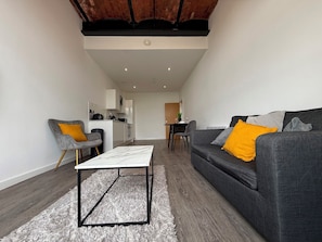 Ein modernes Wohnzimmer mit einem grauen Sofa, einem weißen Couchtisch und einem grauen Sessel.