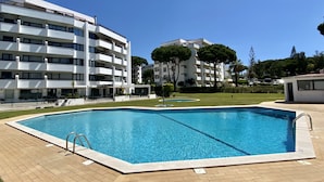 En swimmingpool med en metalstige, omgivet af en murstensplads.