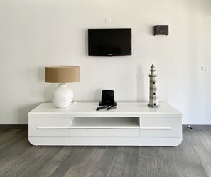Eine weiße Unterhaltungseinrichtung mit Fernseher, Lampe, Fernbedienung und einer dekorativen Leuchtturmfigur.