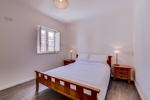 Ein Schlafzimmer mit einem hölzernen Bett, zwei Nachttischen, einer Stehlampe und einer Deckenleuchte.