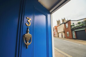 Une porte bleue avec une plaque de numéro en laiton et un heurtoir.