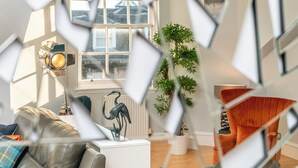 Ein modernes Wohnzimmer mit einer Couch, einer Lampe, einem Blumentopf, einer Heizung und einem Fenster.