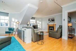 A spacious living area with a high ceiling, a fireplace, a television, and a seating arrangement. - Stylish Hideaway in Central Edinburgh - Pass the Keys (Edinburgh)