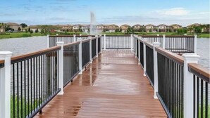 Eine Holzterrasse mit Geländern, die zu einem Gewässer führt, umgeben von Häusern.