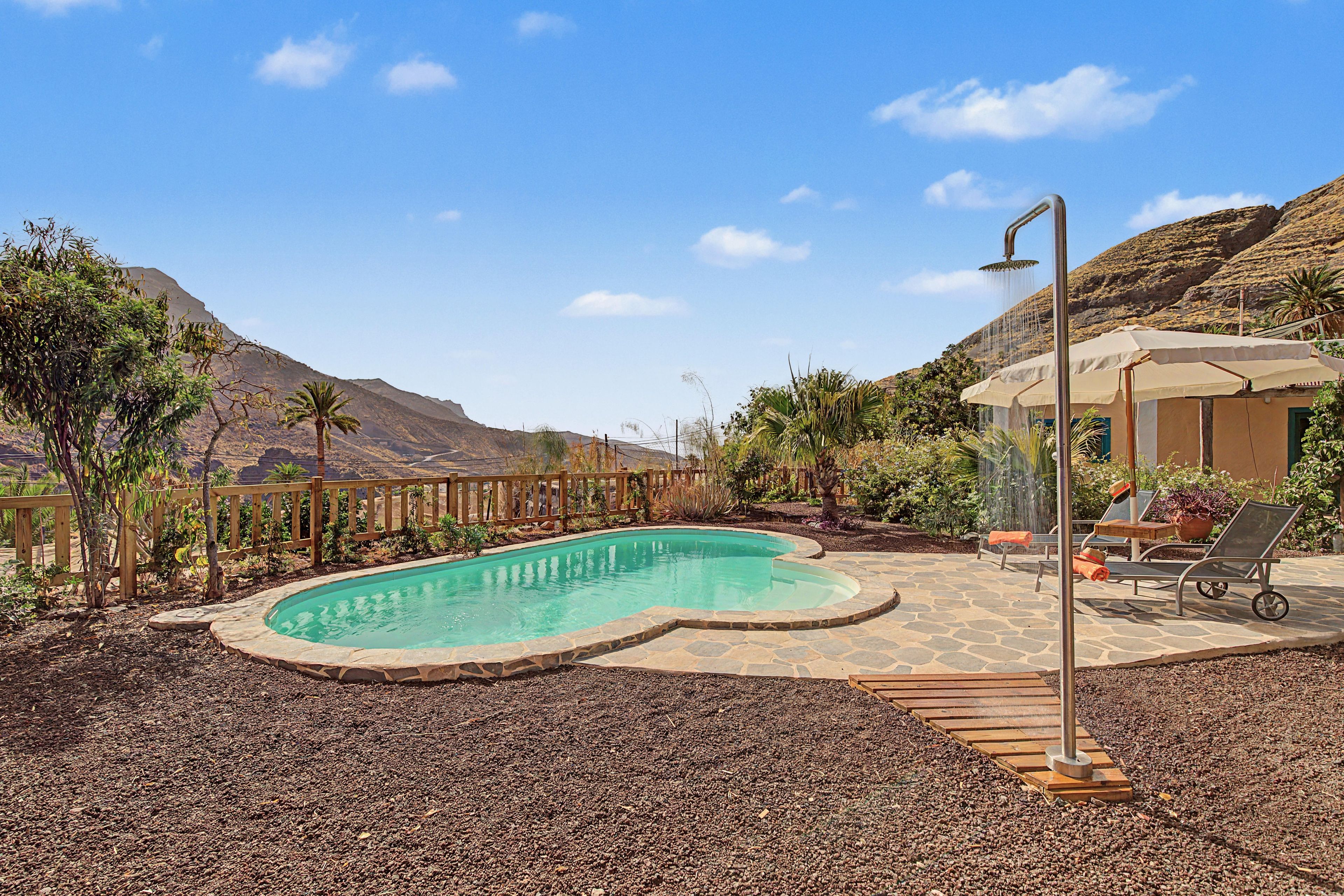 Ein Schwimmbecken mit Holzterrasse und Duschbrause.