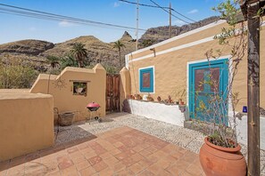 A courtyard with a barbecue grill, a potted plant, and a blue door. - El Patio de Agaete Country House with Sea Views, Private Pool and Wi-Fi (Agaete)