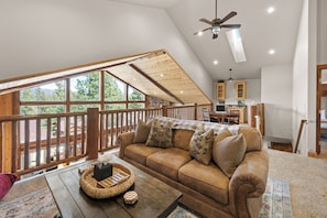A loft-style room with a wooden ceiling, a sofa, a coffee table, and a view of the outdoors. - New on VRBO! 5-Star Modern Mountain Luxury, Hot Tub, Game Room, Pet Friendly (Big Bear Lake)