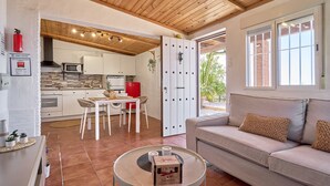 A modern kitchen with white cabinets, a red refrigerator, and a dining area with a table and chairs.