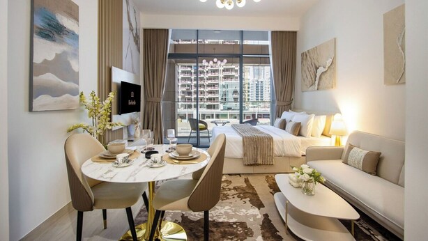 A modern hotel room with a bed, sofa, dining table, and chairs. - New Studio w/ Balcony & Pool | Riviera Beachfront (Dubai)