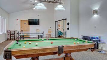 A pool table with balls, a ceiling fan, and a billiard table in a room with a carpeted floor.