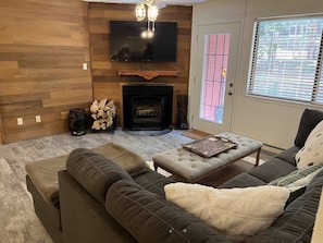A living room with a fireplace, a sofa, a coffee table, and a television mounted on the wall. - Giant Steps Unit 38 Ski in/ Ski out (Brian Head)