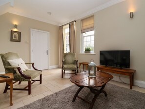 A living room with a television, two armchairs, a coffee table, and a door. - The Bothy (Knaresborough)