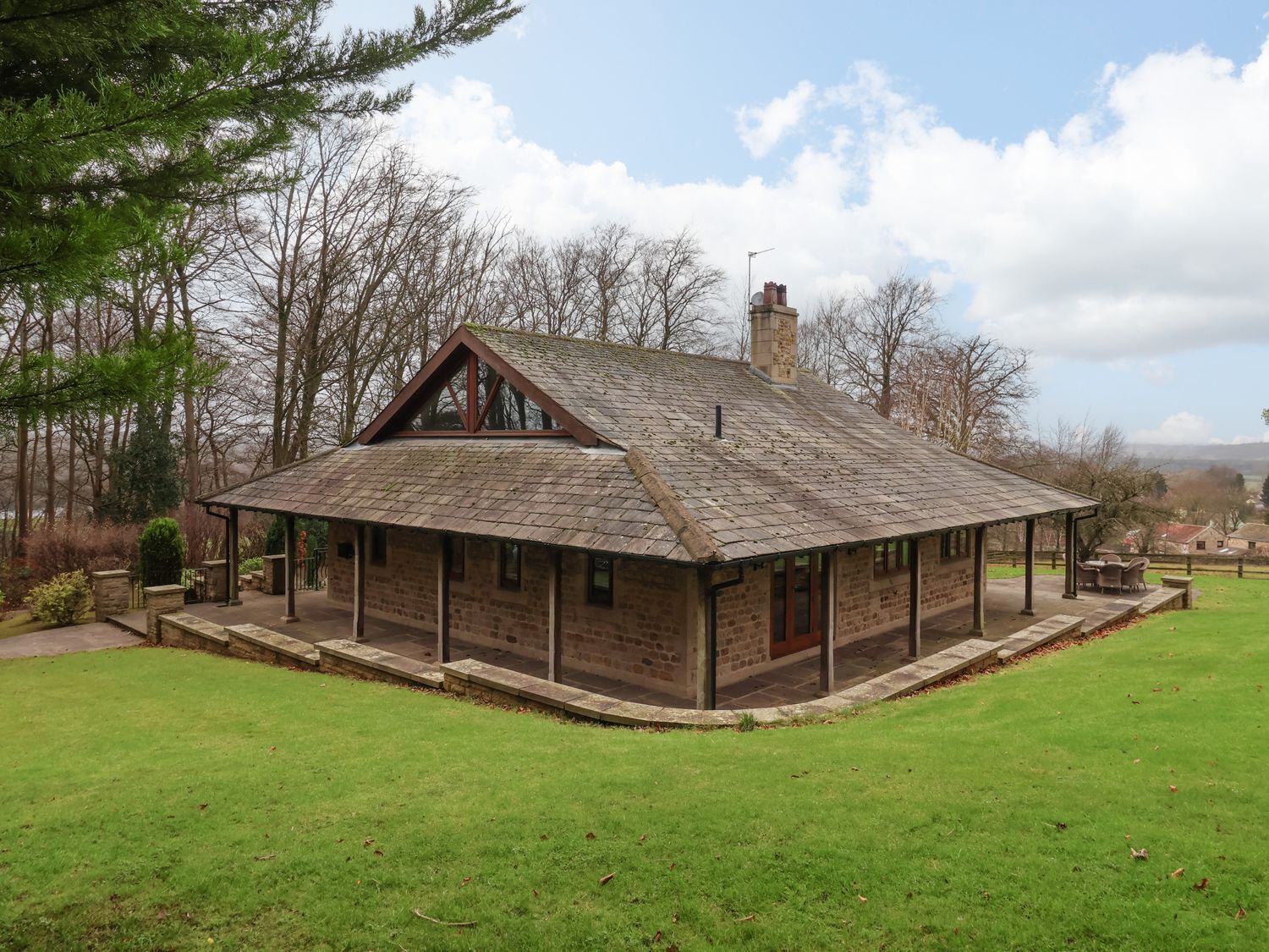 A stone building with a pitched roof, a chimney, and a small porch area.