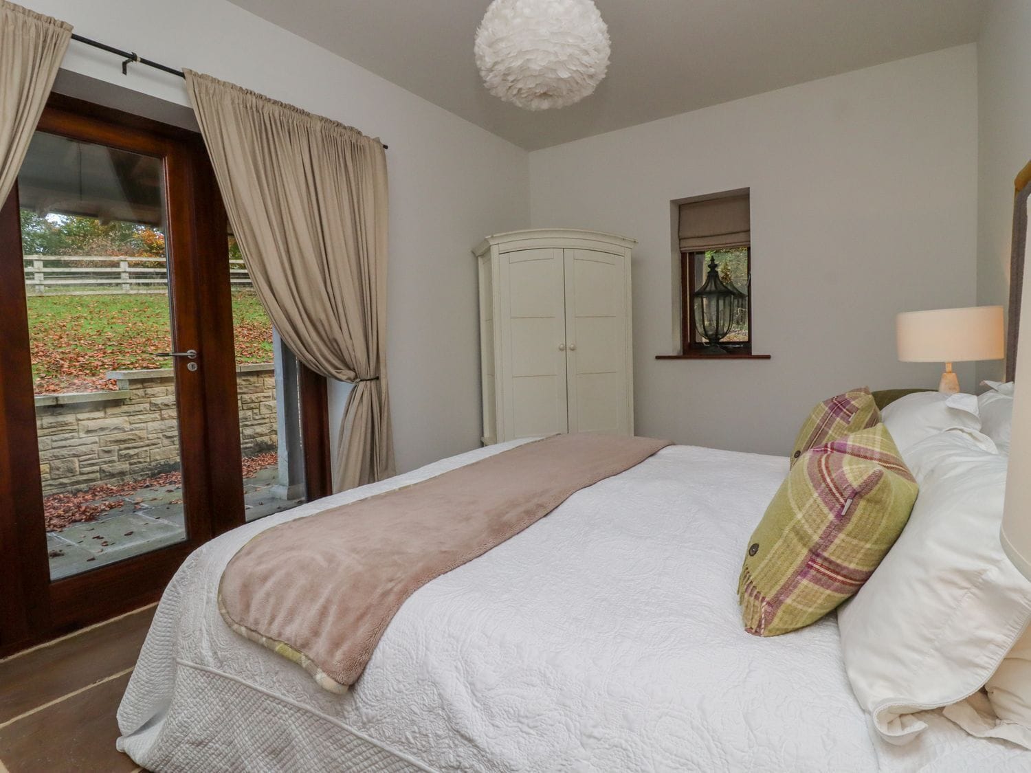 Un dormitorio con cama, armario, ventana con vistas y puerta que da a un espacio exterior.