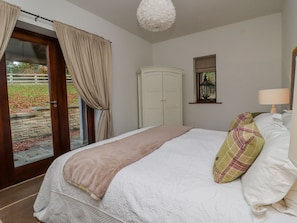 A bedroom with a bed, a wardrobe, a window with a view, and a door leading to an outdoor area. - Sandy Gate (Knaresborough)