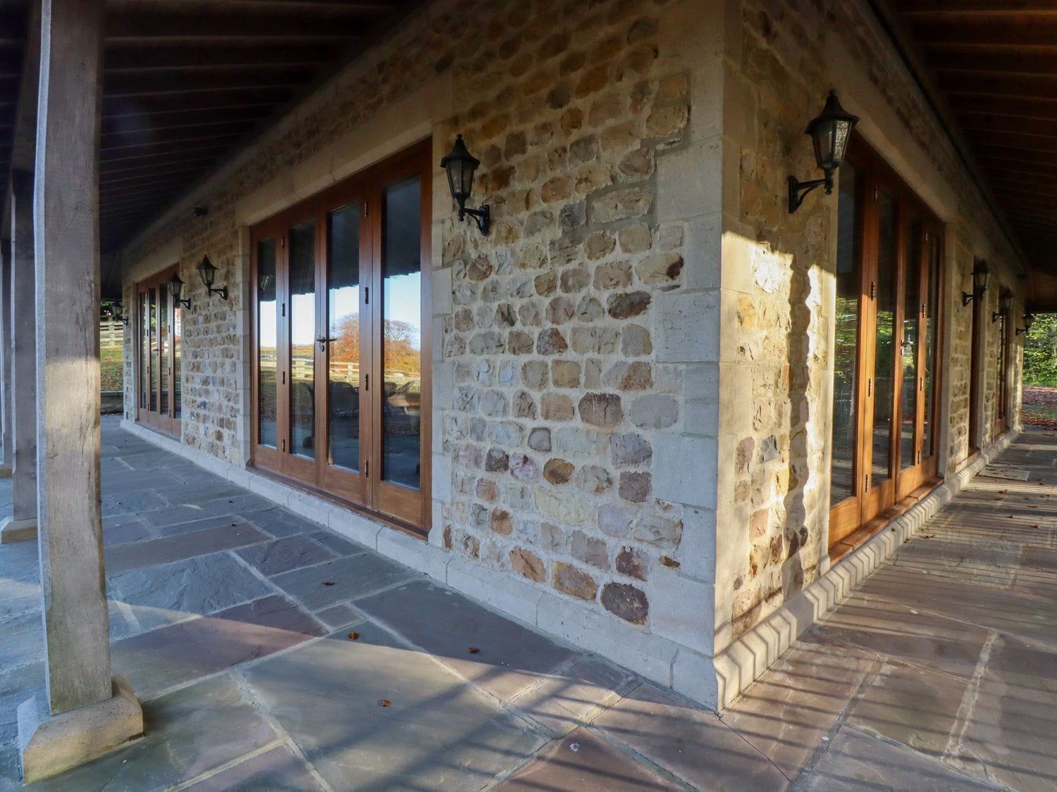 Un edificio de piedra con ventanas amplias y un corredor cubierto.