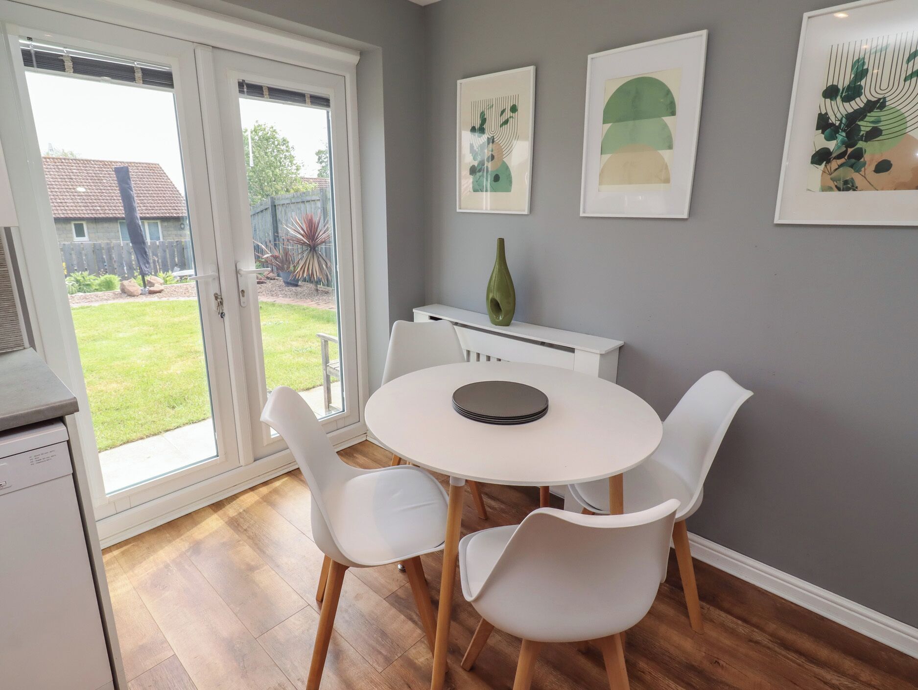 A dining area with a round table, white chairs, and a white cabinet.