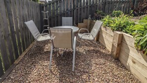A patio with a table and chairs, surrounded by a wooden fence and plants. - 26 Field Court (Wooler)