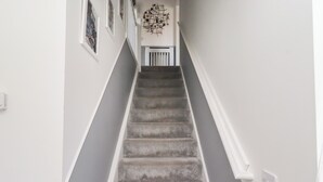 A staircase with a handrail, a wall-mounted light fixture, and a vent. - 26 Field Court (Wooler)