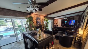 A bar area with a stone floor, a ceiling fan, and a television. - The LaPearla Experience - A Hidden Gem (Riverdale)