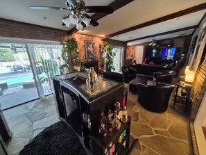 A bar area with a stone floor, a ceiling fan, and a television.