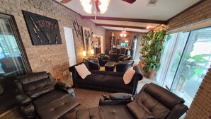 A living room with leather sofas, a brick wall, and a large window. - The LaPearla Experience - A Hidden Gem (Riverdale)