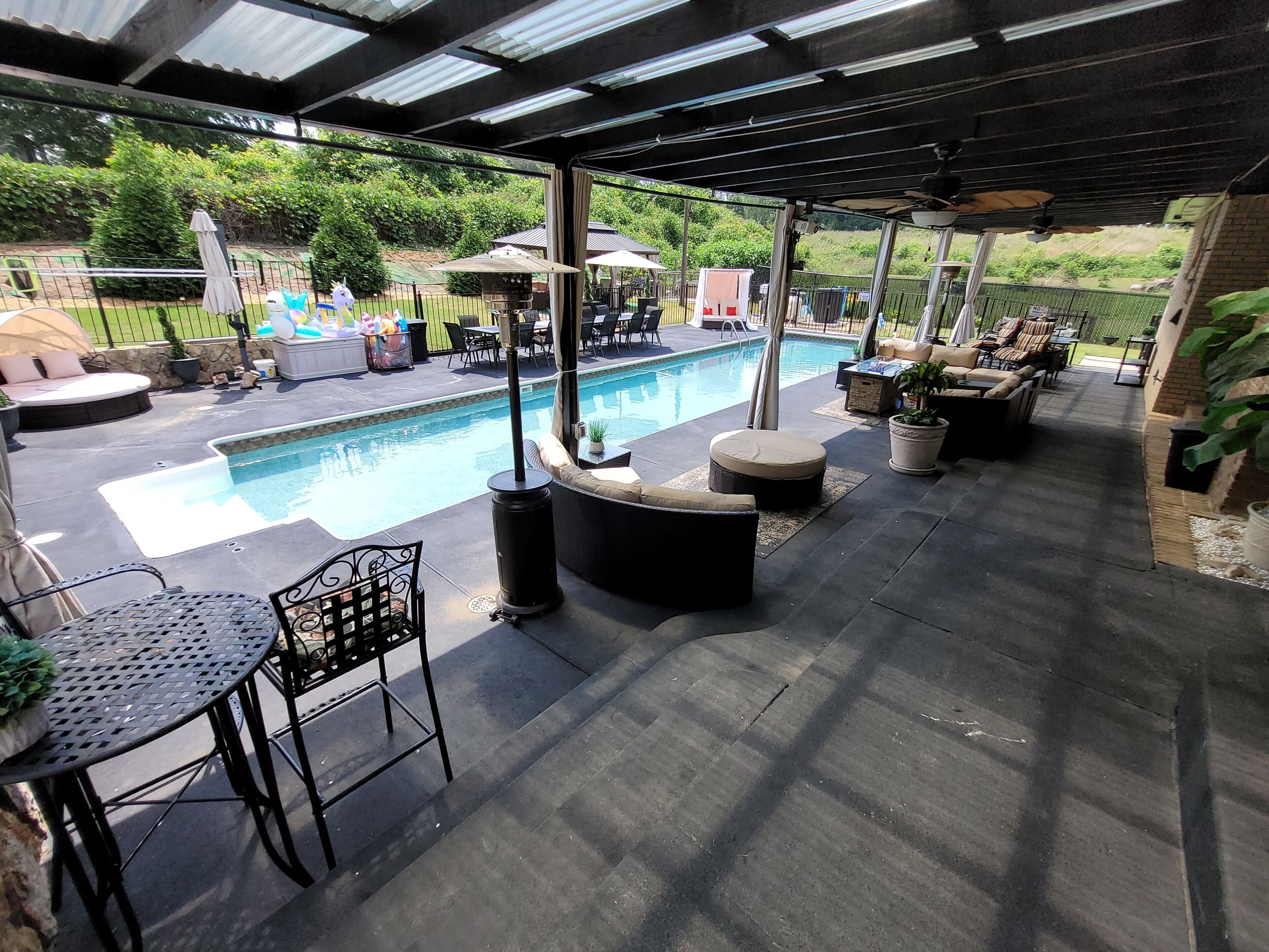 A covered outdoor area with a pool, seating, and potted plants.