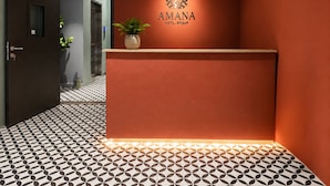 Uma mesa de recepção com um logotipo e a inscrição 'AMANA HOTEL GROUP' na parede.