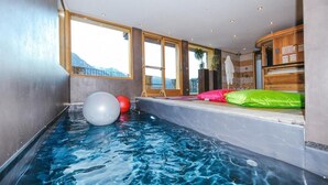 Piscina interior com vista para montanhas, bolas de exercício e armários de madeira.