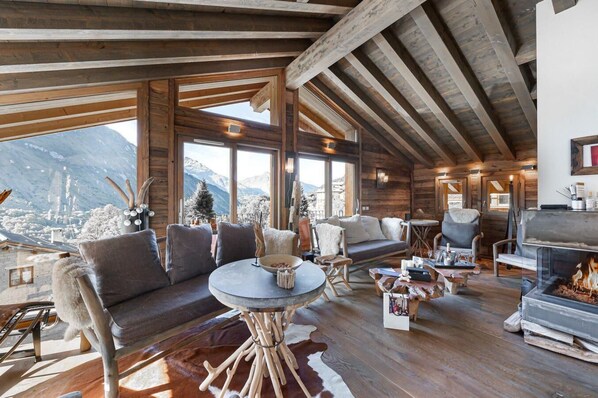 A cozy log cabin interior with a fireplace, wooden beams, a sofa, and a dining area. - Chalet, Ground floor, balcony, fireplace or stove, tv, ski locker, 380m², Saint Martin de Belleville (Saint-Martin-de-Belleville)