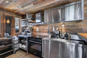 A modern kitchen with stainless steel appliances, wooden paneling, and a built-in oven. - Chalet, Ground floor, balcony, fireplace or stove, tv, ski locker, 380m², Saint Martin de Belleville (Saint-Martin-de-Belleville)