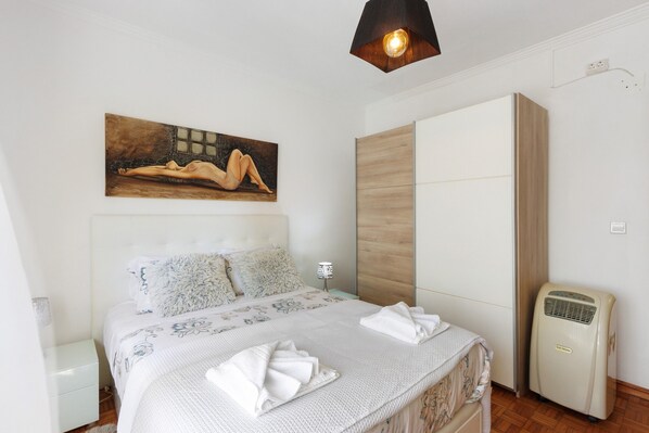 Ein Schlafzimmer mit Bett, einem Bild, einem Kleiderschrank und einem Heizkörper.
