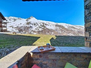 A stone wall with a tray of coffee and cups, a bench, and a mountain view. - Ground floor, swimming pool, balcony, tv, ski locker, 50m², Les Menuires (Les Menuires)