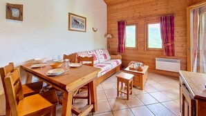Una cabaña de madera con una mesa de comedor, un sofá y una pequeña cocina.