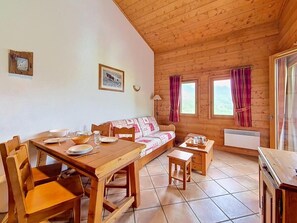 A wooden cabin with a dining table set, a sofa, and a small kitchen area. - 3rd floor, swimming pool, balcony, tv, ski locker, 50m², Les Menuires (Les Menuires)