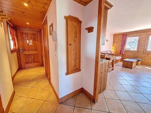 A wooden interior with a tiled floor, a wooden door, a small table, and a window with curtains. - 2nd floor, swimming pool, balcony, tv, ski locker, 50m², Les Menuires (Les Menuires)