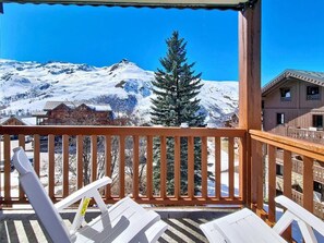 A wooden balcony with white chairs, a snow-covered mountain in the background, and a pine tree. - 2nd floor, swimming pool, balcony, tv, ski locker, 50m², Les Menuires (Les Menuires)