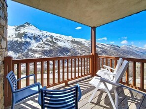 Ein Balkon mit Holzbalkon, zwei blaue und zwei weiße Stühle.