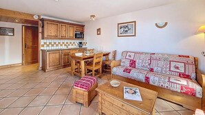 Una sala acogedora con un sofá, una mesa de madera y una cocina al fondo.