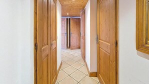 Un pasillo con puertas de madera y piso de baldosas.