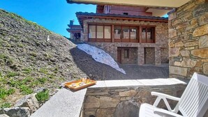 A stone building with a balcony, a stone wall, and a white chair. - 100m from ski slopes, 2nd floor, swimming pool, balcony, tv, ski locker, 46m², Les Menuires (Les Menuires)