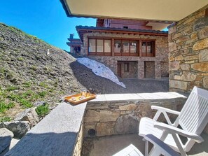 A stone building with a balcony, a stone wall, and a white chair. - 100m from ski slopes, 2nd floor, swimming pool, balcony, tv, ski locker, 46m², Les Menuires (Les Menuires)
