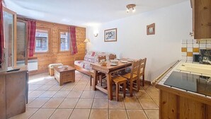 A wooden interior with a dining table, chairs, a sofa, and a kitchen area. - 100m from ski slopes, 2nd floor, swimming pool, balcony, tv, ski locker, 46m², Les Menuires (Les Menuires)
