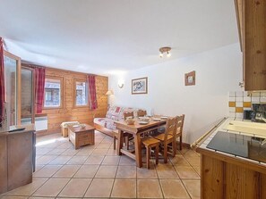 A wooden interior with a dining table, chairs, a sofa, and a kitchen area. - 100m from ski slopes, 2nd floor, swimming pool, balcony, tv, ski locker, 46m², Les Menuires (Les Menuires)