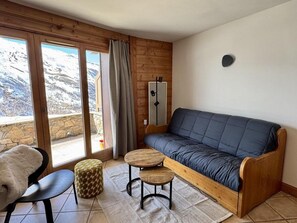 Ein gemütliches Zimmer mit einer Couch, einem Sessel und einem kleinen Tisch.