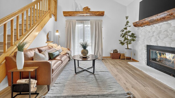 Ett vardagsrum med en trappa, en öppen spis, en soffa och ett soffbord.