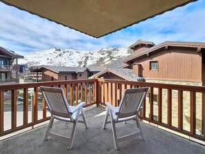 A balcony with two white chairs, a wooden railing, and a view of snow-covered mountains. - 1st floor, swimming pool, balcony, tv, ski locker, 32m², Les Menuires (Les Menuires)