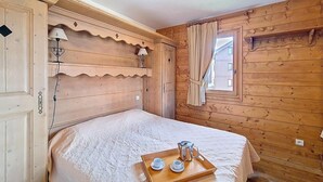 A wooden room with a bed, a tray with cups and a pot, and a window with curtains. - 100m from ski slopes, 1st floor, swimming pool, balcony, tv, ski locker, 32m², Les Menuires (Les Menuires)