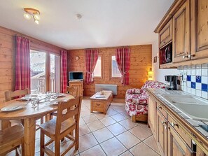 A cozy cabin interior with a dining area, a sofa, a TV, and a kitchen. - 1st floor, swimming pool, balcony, tv, ski locker, 32m², Les Menuires (Les Menuires)